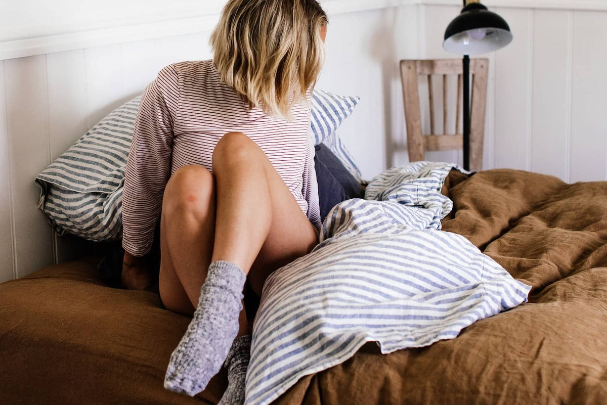 A woman wearing socks sitting on bed