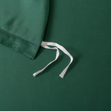 Flat-lay image of a dark green fabric drawstring bag on matching surface, made from premium bamboo materials. The white drawstrings contrast with the deep green background, echoing the essence of Linenly���s Bamboo Quilt Cover - Ever