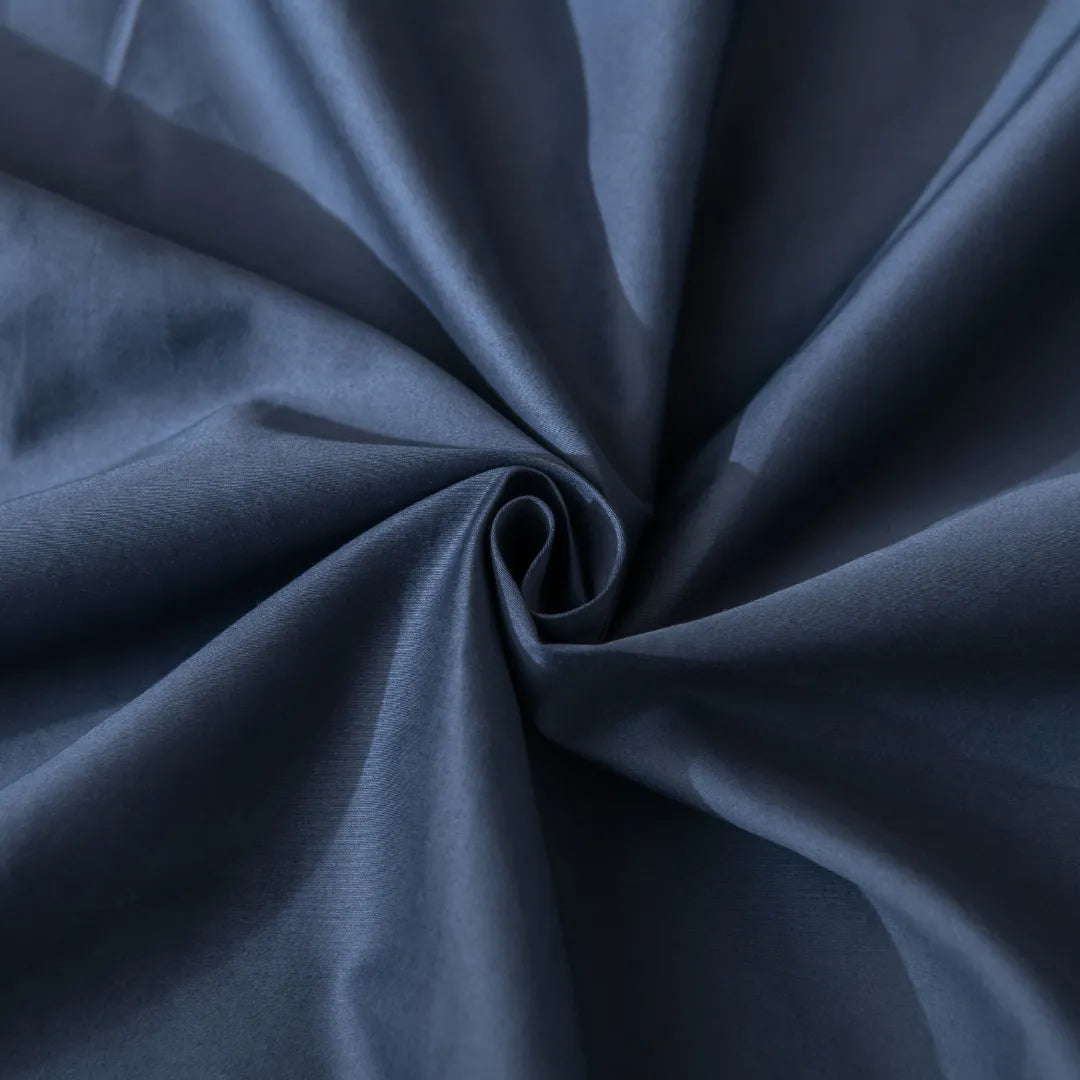 Close-up of Linenly’s Luxe Cotton Sateen Sheet Set in Midnight, showcasing its soft, high thread count fabric artfully gathered to form elegant swirling folds and textured creases.
