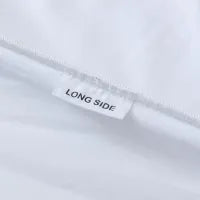 A white fabric tag with the words "LONG SIDE" in black text is sewn into the seam of a white textile, likely indicating the longer edge of the fabric.